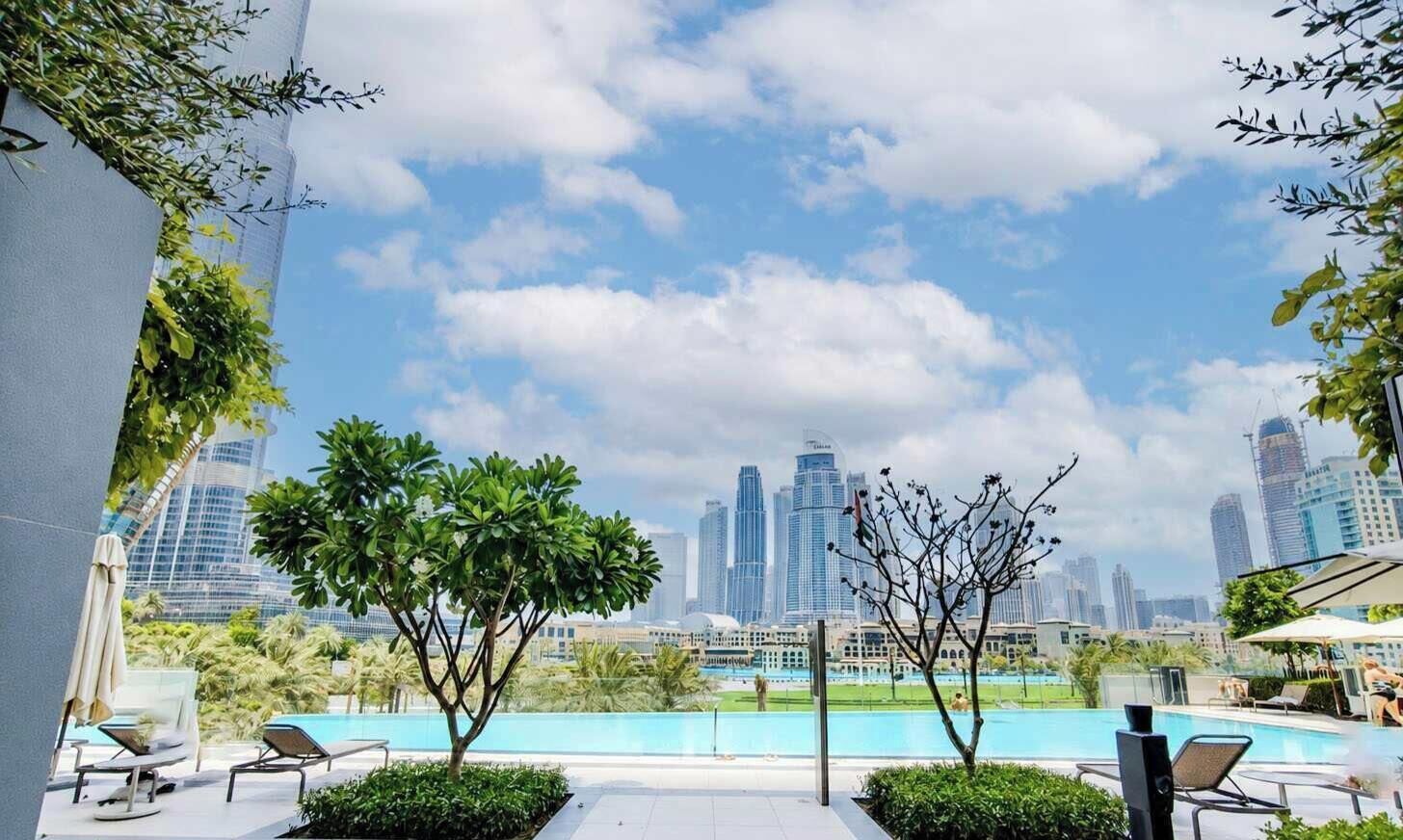 A rooftop pool area with lounge chairs and a view of a city skyline.