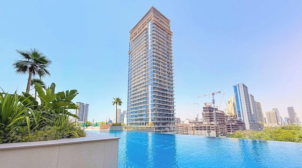 Un immeuble de grande hauteur avec une piscine en premier plan.