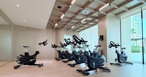 Ein Fitnessraum mit mehreren in Reihen angeordneten Ergometerbikes, großen Fenstern und einer hohen Decke mit eingelassener Beleuchtung.
