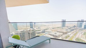 A balcony with a view of a cityscape, including high-rise buildings and a clear sky. - Modern 1BR, Binghatti Royale, JVC (Dubai)