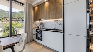 Eine moderne Küche mit Marmor-Spritzschutz, Holzschränken und Blick auf eine gebirgige Landschaft durch große Fenster.