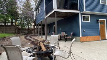 A two-story building with a covered patio area featuring outdoor furniture and a fire pit.