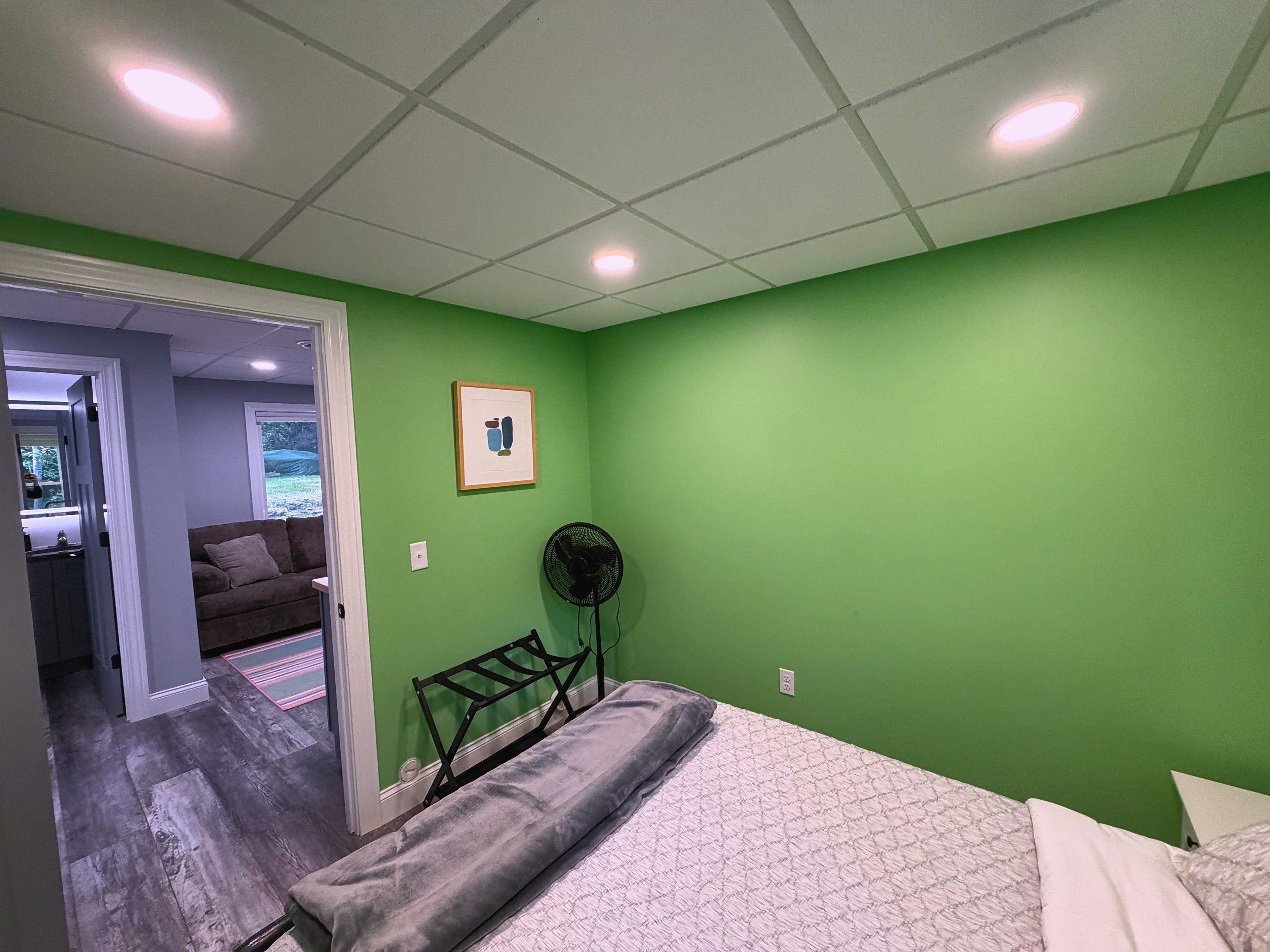 Quarto com cama, ventoinha e parede verde.