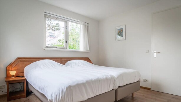 Une chambre à coucher avec un lit, une lampe de chevet, une fenêtre et une porte.