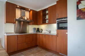 A kitchen with wooden cabinets, a stainless steel range hood, a Siemens oven, and a coffee maker.