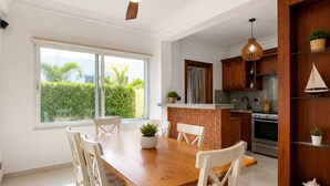 Una cucina moderna con zona pranzo, con un tavolo in legno, sedie bianche e una ventola a soffitto.