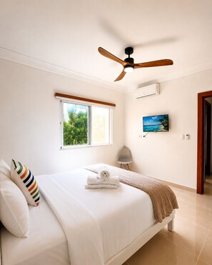 Une chambre à coucher comprenant un lit, un ventilateur de plafond, une fenêtre avec vue, un appareil de climatisation et un téléviseur.