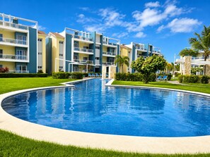 Un hôtel moderne doté d’une piscine centrale, de nombreux balcons et d’un aménagement paysager luxuriant.