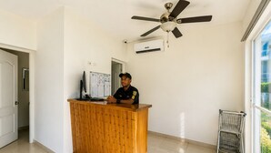 Una reception con ventilatore a soffitto, impianto di condizionamento, monitor computer e finestra vista verde.
