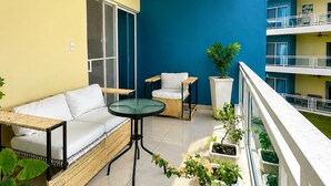 Un balcone con divano, tavolo, sedie, piante in vaso e ventola a soffitto.