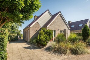 A house with a sloped roof, a paved driveway, and a well-maintained garden. - Texel Getaway with Whirlpool (De Koog)