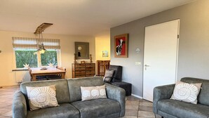 Ein Wohnzimmer mit zwei grauen Sofas, einem Holzesstisch und einem Deckenventilator.