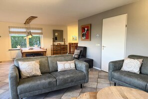 Ein Wohnzimmer mit zwei grauen Sofas, einem Holzesstisch und einem Deckenventilator.