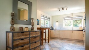 Eine moderne Küche mit Kochinsel, Holzschränken und einem großen Fenster für natürliches Licht.