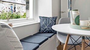 A room with a window seat, a round table, and a view of a building outside. - Stylish 2-Bed Villa · Central Edinburgh (Edinburgh)