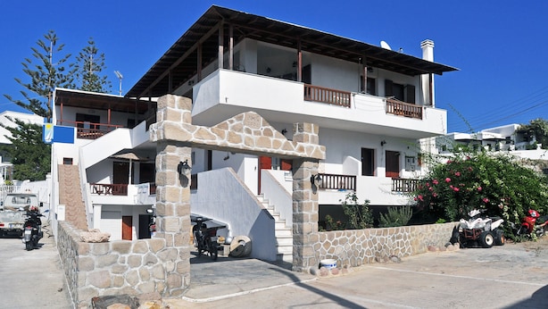 A two-story building with a stone facade, balconies, and a staircase leading to the upper level. - Kyanee (Adamantas)