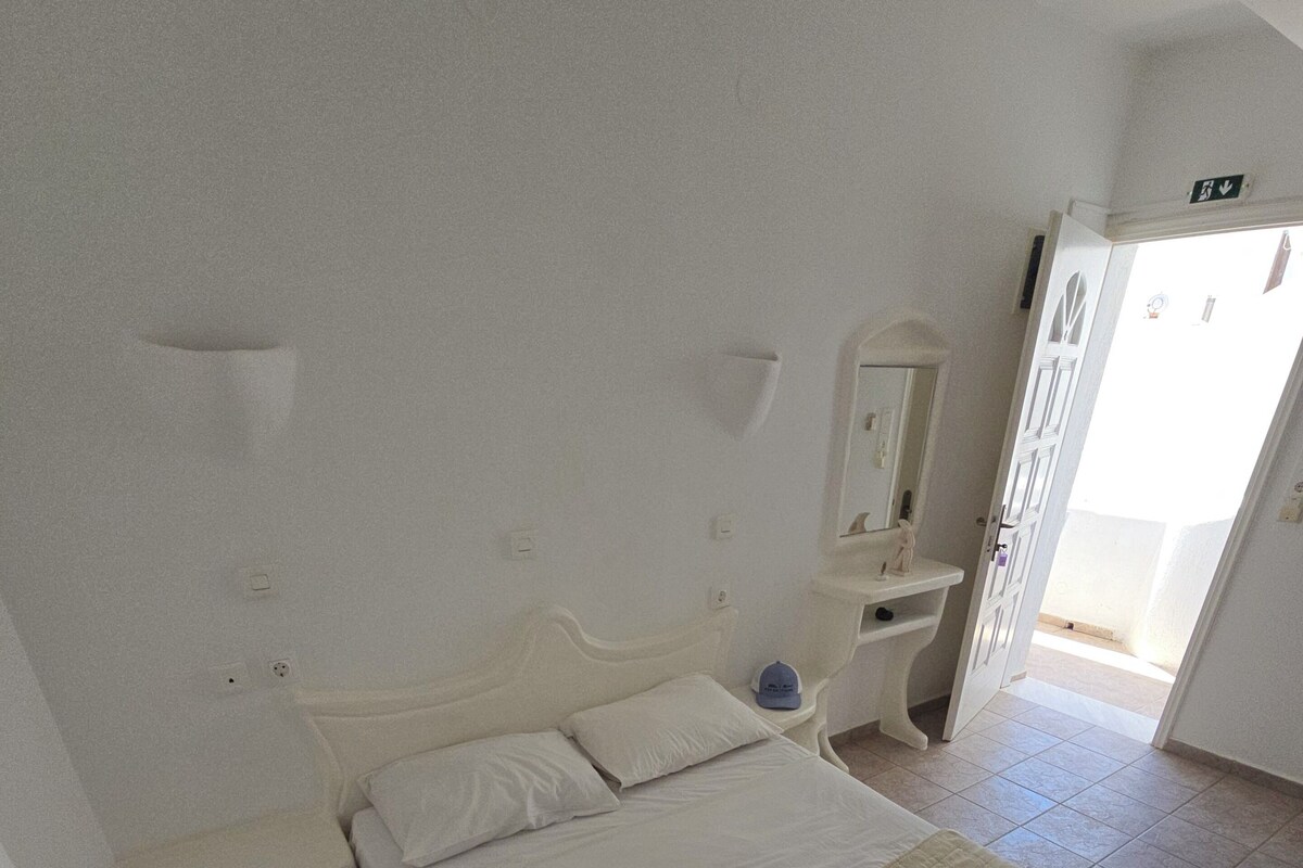Ein Hotelzimmer mit Bett, Nachttisch, Spiegel und einer Tür zu einem Außenbereich.