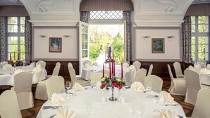 Comedor formal con mesas redondas, manteles blancos y sillas.