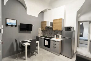 Una cucina compatta con forno a incasso, microonde e lavello.
