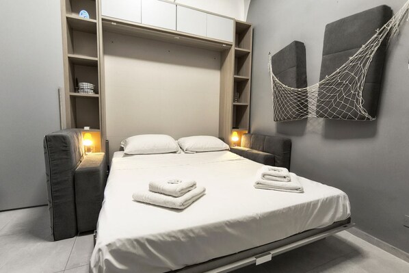 A modern bedroom with a bed, bedside tables, a built-in wardrobe, and a hammock.