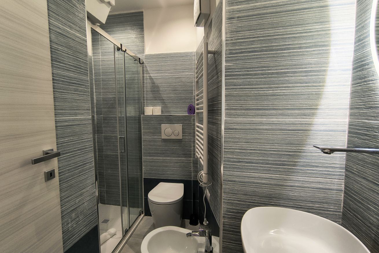 A modern bathroom with a glass shower enclosure, a toilet, and a sink.