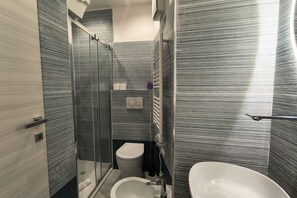 Un bagno moderno con box doccia in vetro, un water e un lavandino.