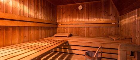 A sauna room with wooden benches and a wooden bucket.