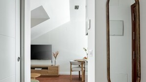 A modern interior with a wooden floor, a large mirror, a television, and a small table with a vase. - Charming penthouse in a prime location (Madrid)