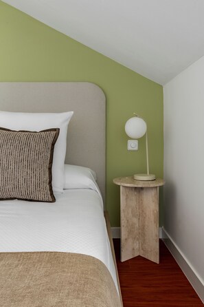A bed with a white headboard, a brown pillow, and a bedside table with a white lamp. - Charming penthouse in a prime location (Madrid)