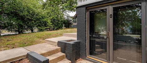 A modern building with a number 411 sign, a glass door entrance, and a concrete staircase leading to a patio area.