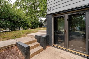 Ein modernes Gebäude mit der Hausnummer 411, einem Glastür-Eingang und einer Betonstufenanlage, die zu einer Terrasse führt.