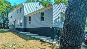 A two-story residential building with a front porch, a garage, and a driveway. - Modern Studio Suite Near DC with Full Kitchen (Arlington)