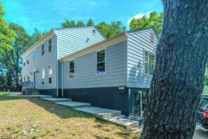 A two-story residential building with a front porch, a garage, and a driveway. - Modern Studio Suite Near DC with Full Kitchen (Arlington)
