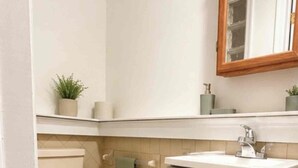 A compact bathroom with a toilet, sink, and cabinet. - Modern Studio Suite Near DC with Full Kitchen (Arlington)