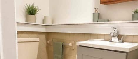 A compact bathroom with a toilet, sink, and cabinet.