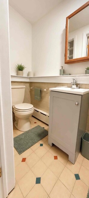 A compact bathroom with a toilet, sink, and cabinet. - Modern Studio Suite Near DC with Full Kitchen (Arlington)