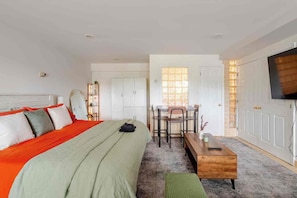 A bedroom with a bed, a desk, and a television. - Modern Studio Suite Near DC with Full Kitchen (Arlington)