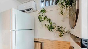 A kitchen with a white refrigerator, a wall-mounted air conditioner, and a radiator. - Modern Studio Suite Near DC with Full Kitchen (Arlington)