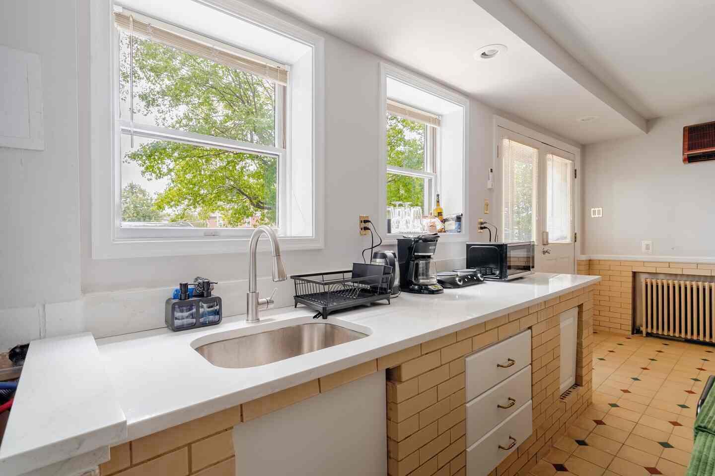 Ett modernt kök med en stor köksö, en diskho i rostfritt stål och en inbyggd mikrovågsugn.