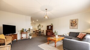 A living room with a sofa, a television, a coffee table, and a dining area with chairs and a table.
