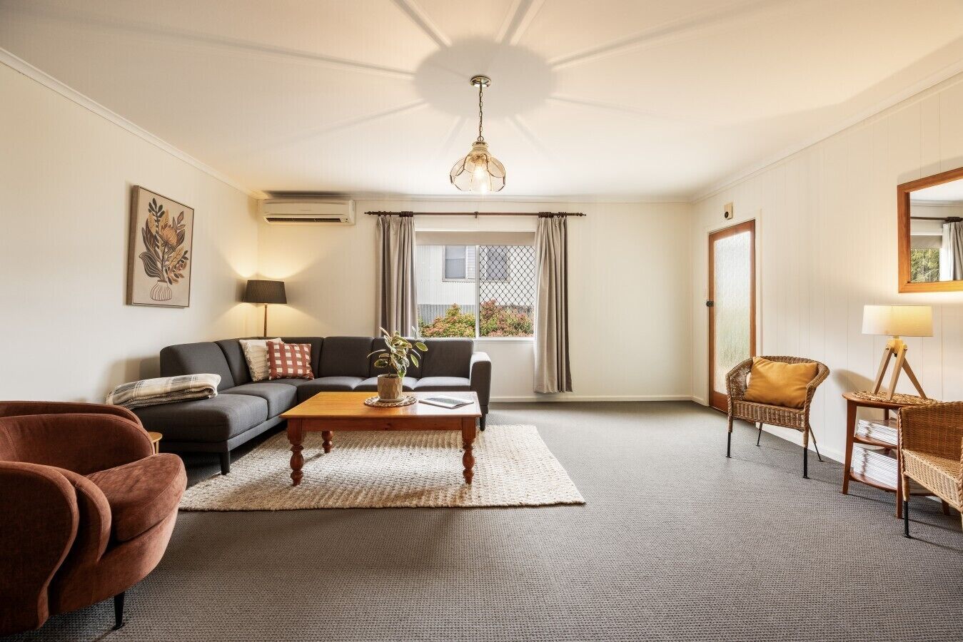 A living room with a sofa, a coffee table, a chair, a lamp, and a window with curtains.