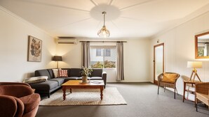 A living room with a sofa, a coffee table, a chair, a lamp, and a window with curtains.