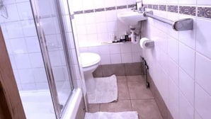 A bathroom with a glass shower enclosure, a toilet, a sink, and a towel on the floor. - Property (London)