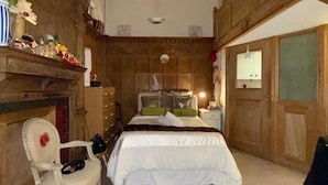 A bedroom with a bed, a chair, a dresser, and a fireplace. - Property (London)