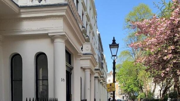 A sidewalk adjacent to a building with white facades and black iron railings. - Property (London)