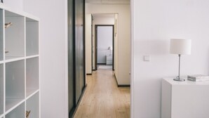 Ein Flur mit Holzboden, weißen Wänden, einem weißen Schrank mit Lampe und einer Tür zu einem anderen Raum.