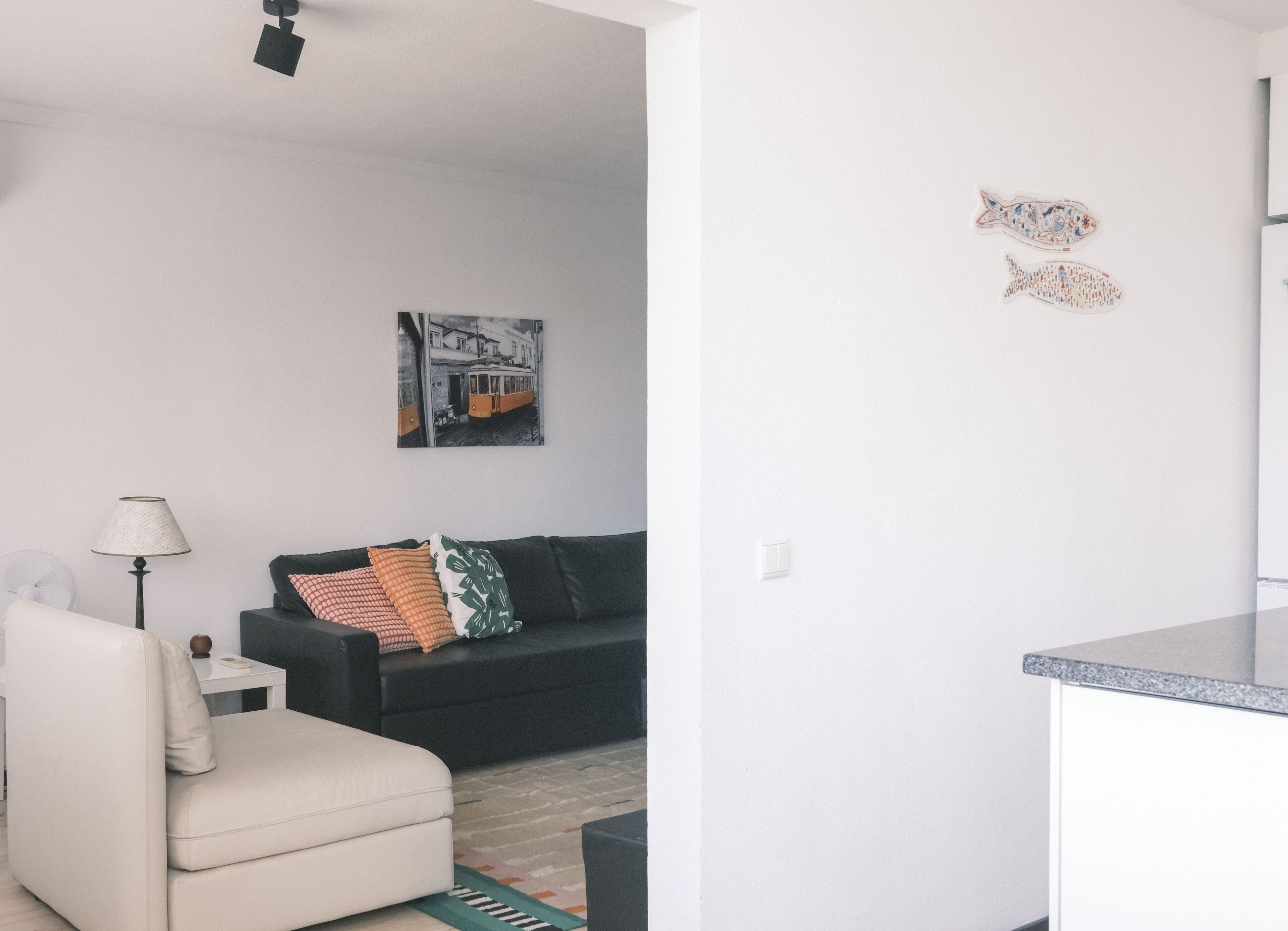 Un salon moderne avec un canapé, une lampe et un tableau encadré accroché au mur.