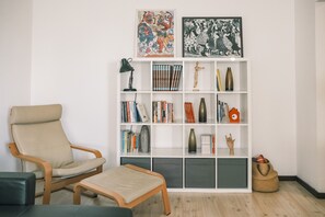 Una sala de estar con un sofá, una mesita, una estantería y un jarrón decorativo.