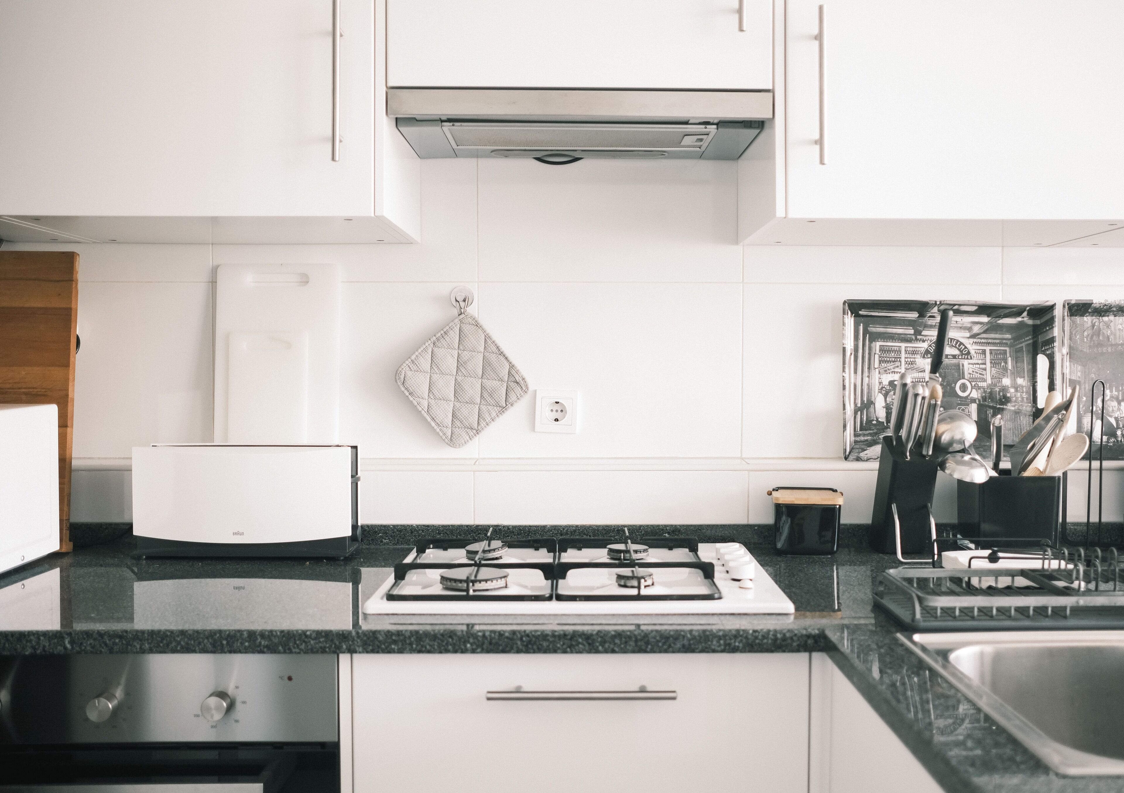 A kitchen with white cabinets, a gas stove, a sink, and a countertop.