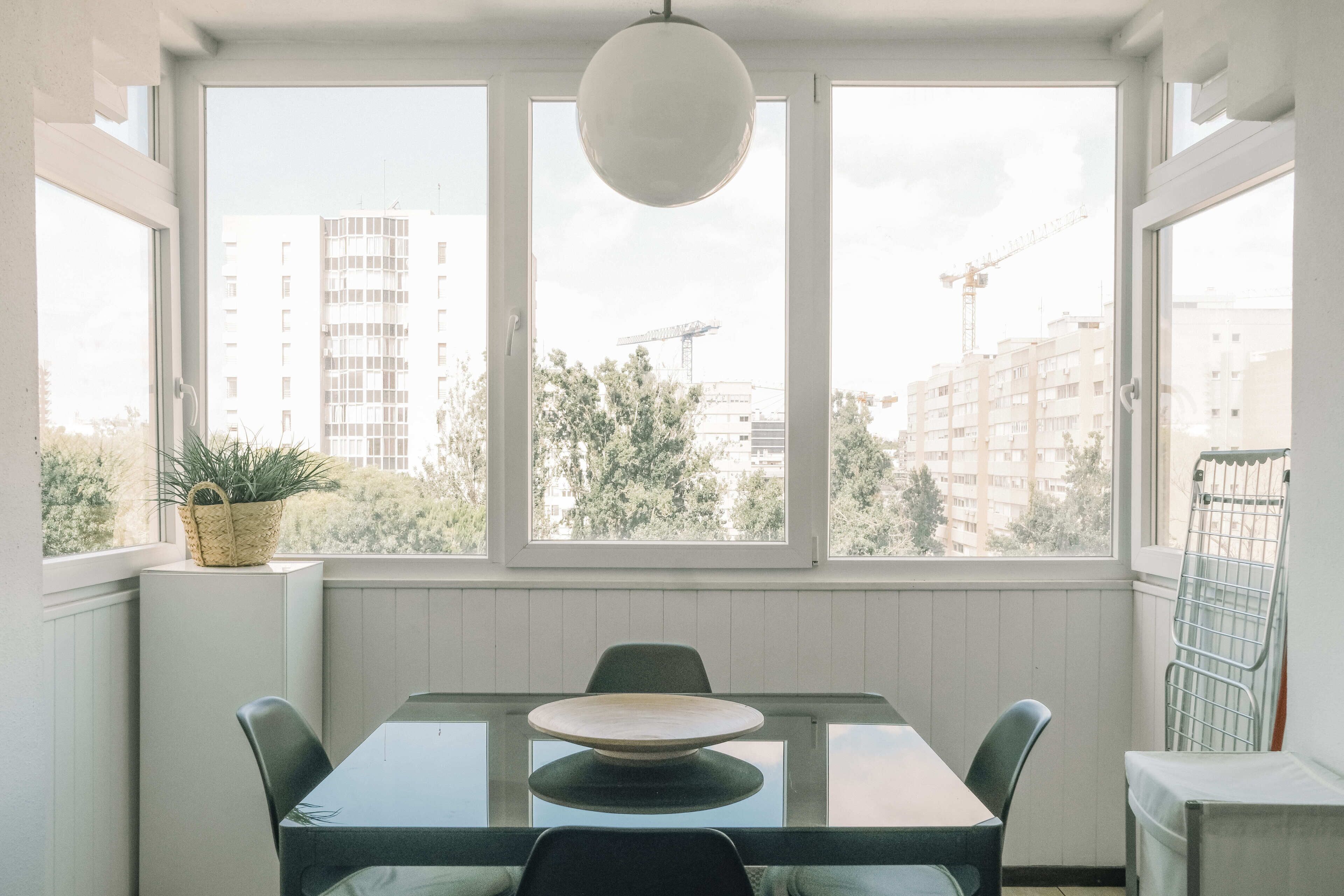 Un espace repas comprenant une table et des chaises, de grandes fenêtres et un luminaire suspendu.